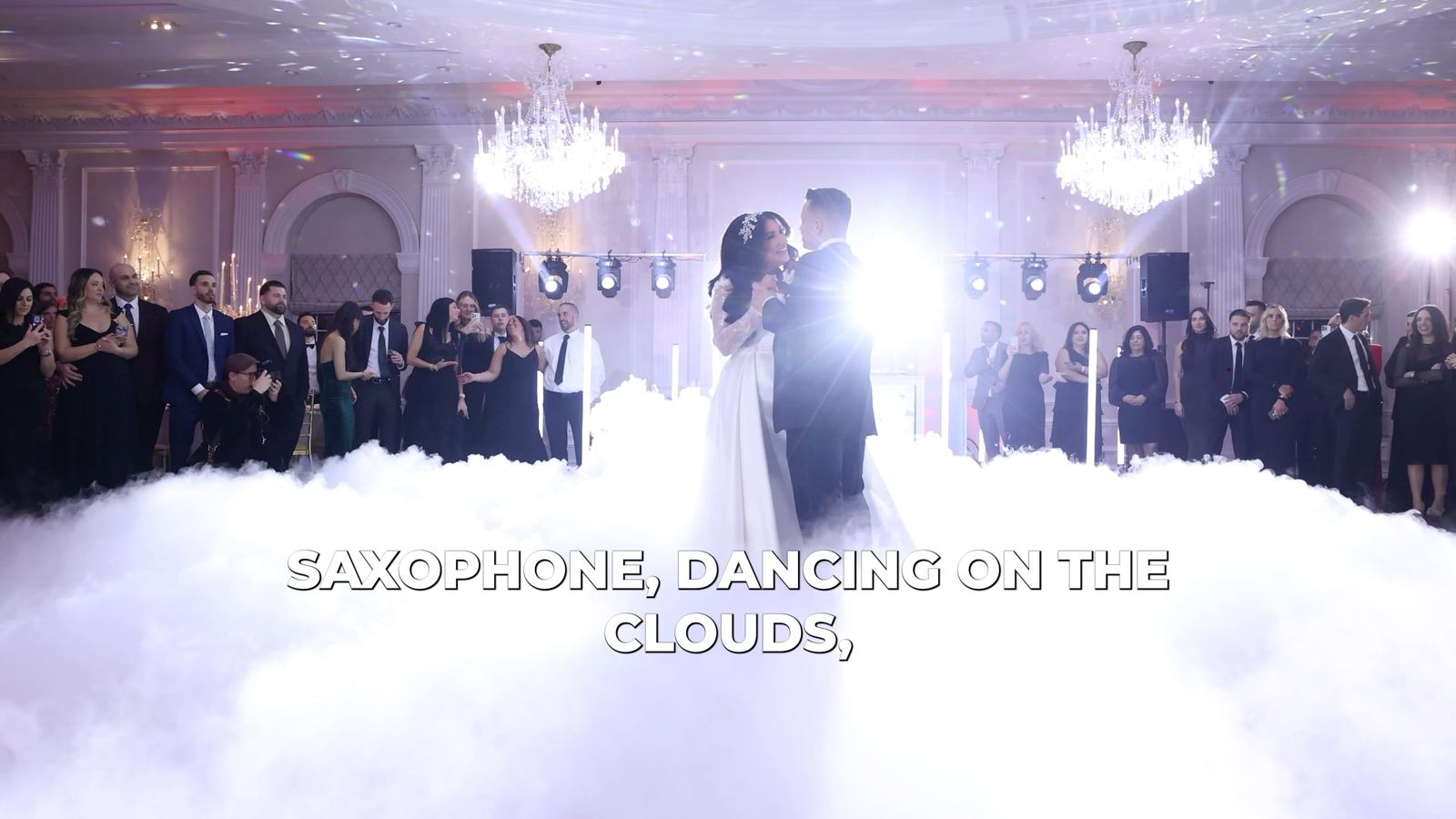 A couple's first dance on a floor covered in low dry-ice fog, lit from the side so the cloud reads on camera