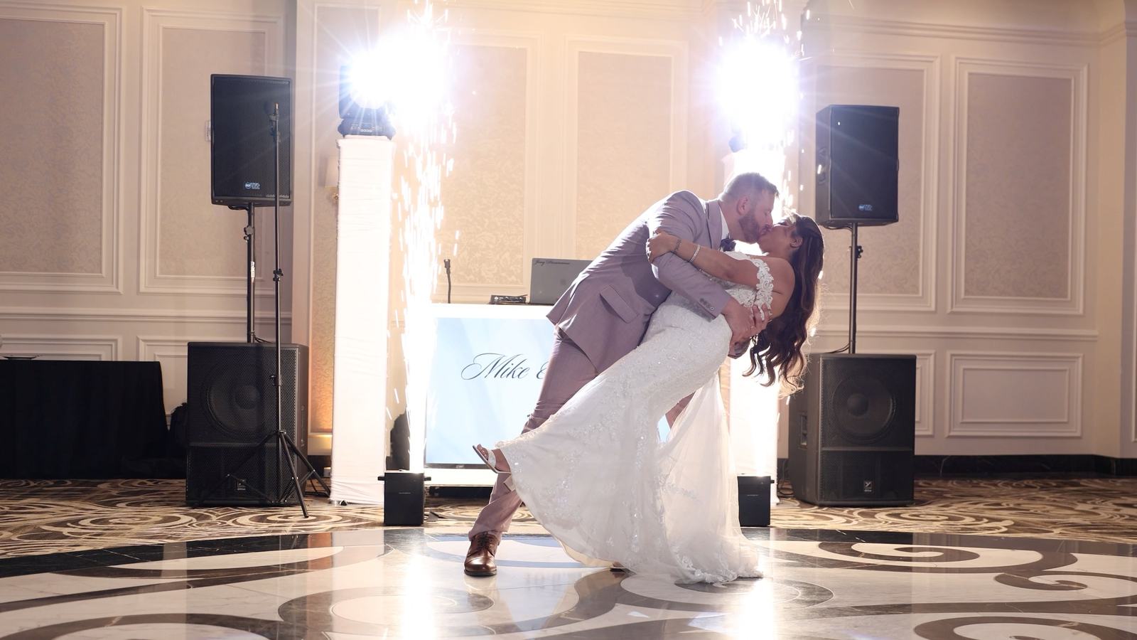 A first dance dip on the marble dance floor at The Meadow Wood, with cold spark fountains firing and the DJ booth and speakers behind