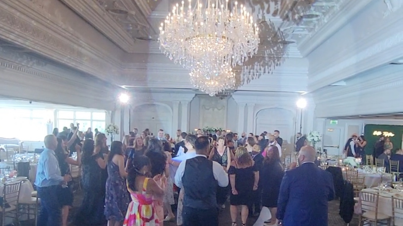 Guests filling the dance floor beneath the crystal chandeliers in the Grand Ballroom at The Park Savoy Estate, garden windows behind them
