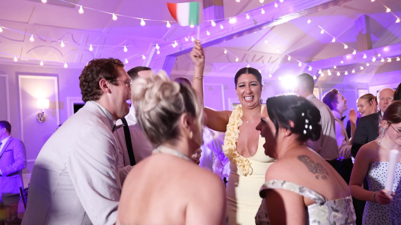 Guests dancing under string lights and purple uplighting at Stewart Manor Country Club, Garden City