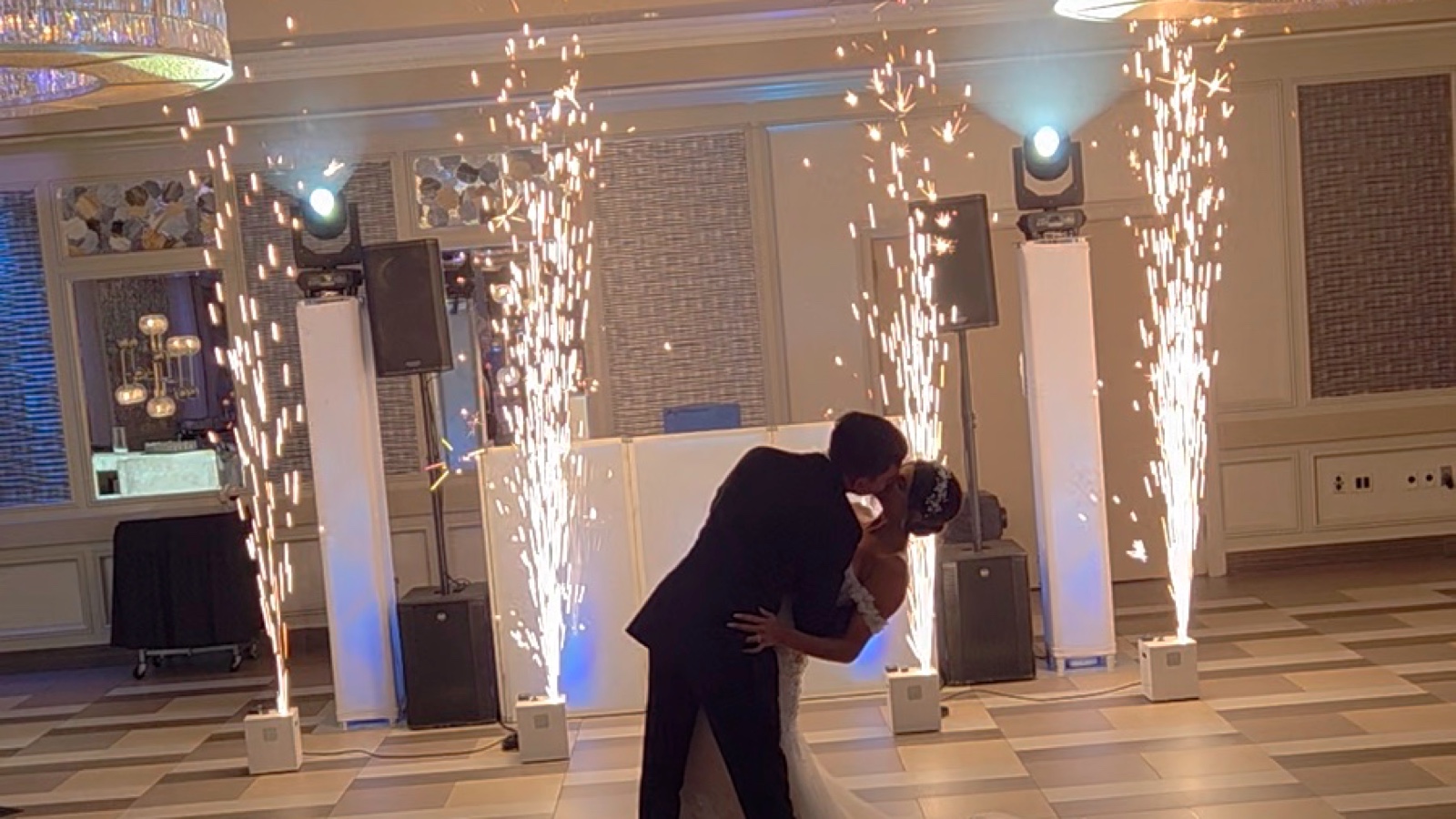 Cold spark fountains firing on either side of the dance floor at Russo's on the Bay as the couple dance, with the Disaronno Events DJ setup and moving-head lighting behind